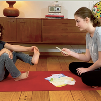 Image of an adolescent girl and an elementary school age girl looking at a DMind Activity  Card